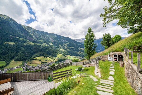 A scenic mountain view with a wooden deck, stone steps, and a rustic building.