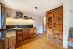 A modern kitchen with wooden cabinetry, a built-in island, and a hanging shelf above the sink.