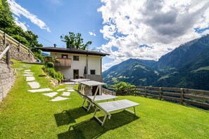 A house with a stone staircase, a balcony, and a view of mountains.