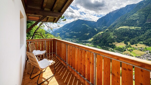 A wooden balcony with wicker chairs, overlooking a mountainous landscape. - Apartment 'Bergchalet Prantach W95' with Mountain View, Shared Terrace and Wi-Fi (San Martino In Passiria)