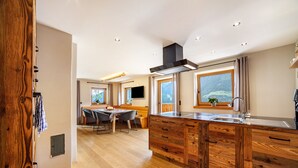 A modern kitchen with wooden cabinetry, a central island, and large windows. - Apartment 'Bergchalet Prantach W95' with Mountain View, Shared Terrace and Wi-Fi (San Martino In Passiria)