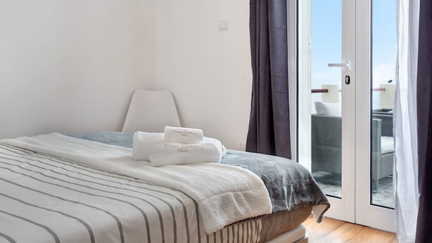 A hotel room with a bed, a chair, a balcony with wicker furniture, and a sliding glass door. - Holiday Home 'Simão House' with Private Terrace, Private Garden and Wi-Fi (Calheta)