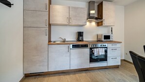 A modern kitchen with a dishwasher, oven, microwave, and a coffee maker.