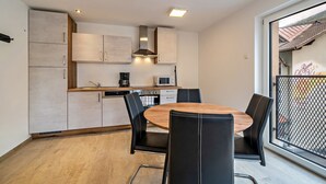 A modern kitchen with a dining area, including a round wooden table and black chairs.
