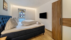 A bedroom with a bed, a wardrobe, a television, and a window.