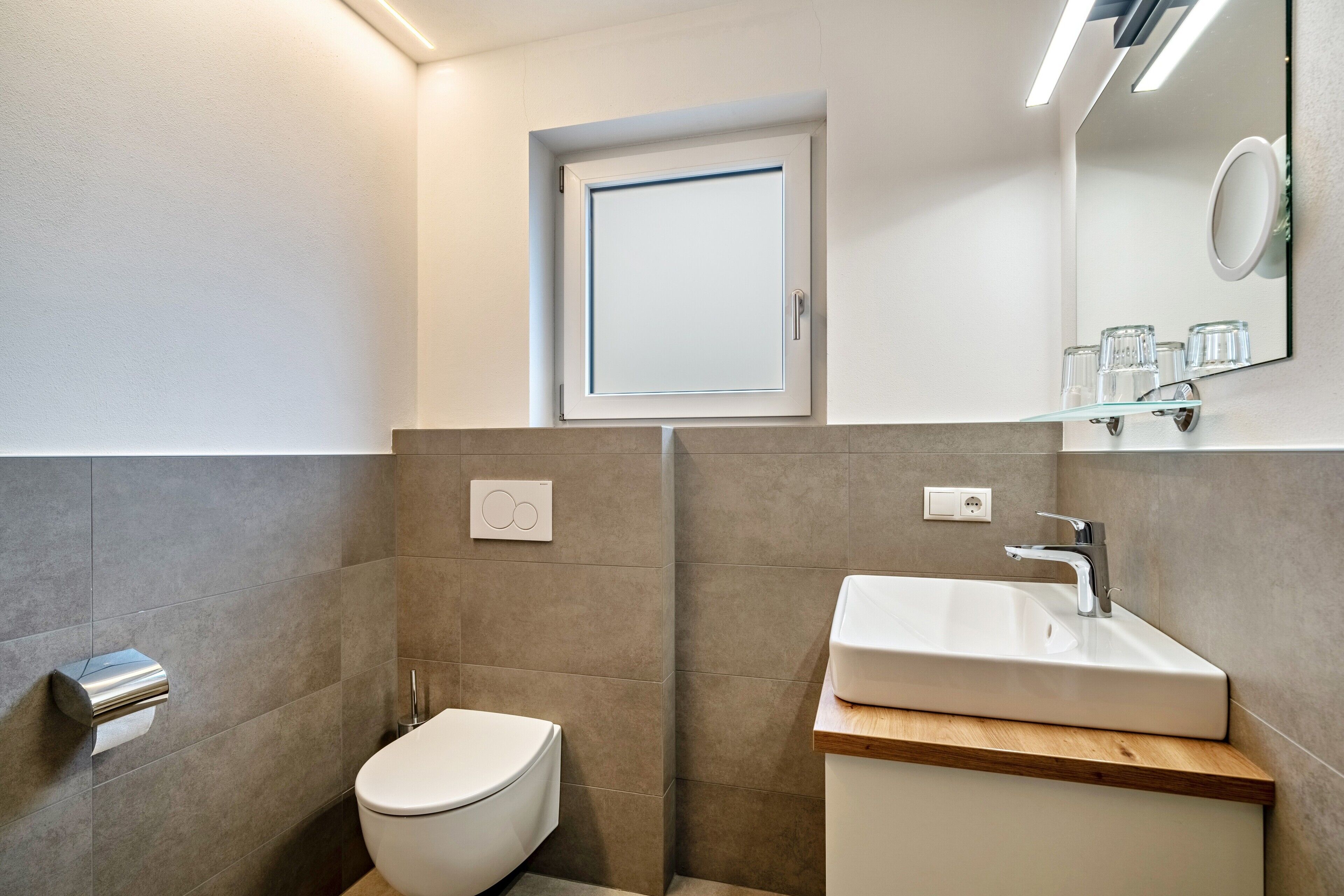 Un bagno moderno con il water, lavandino e specchio.