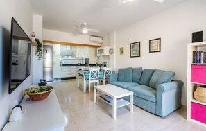 A modern living room with a sofa, a coffee table, and a dining area with a table and chairs.