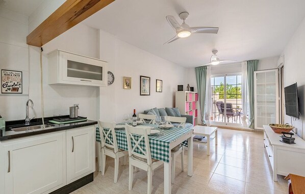 A kitchen with white cabinets, a microwave, and a dining area with a checkered tablecloth.