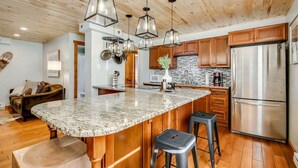 Una cucina con un'isola grande, mobili in legno, elettrodomestici in acciaio inossidabile e illuminazione a sospensione.