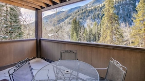 Un balcone con tavolo e sedie, affacciato su un paesaggio montuoso.