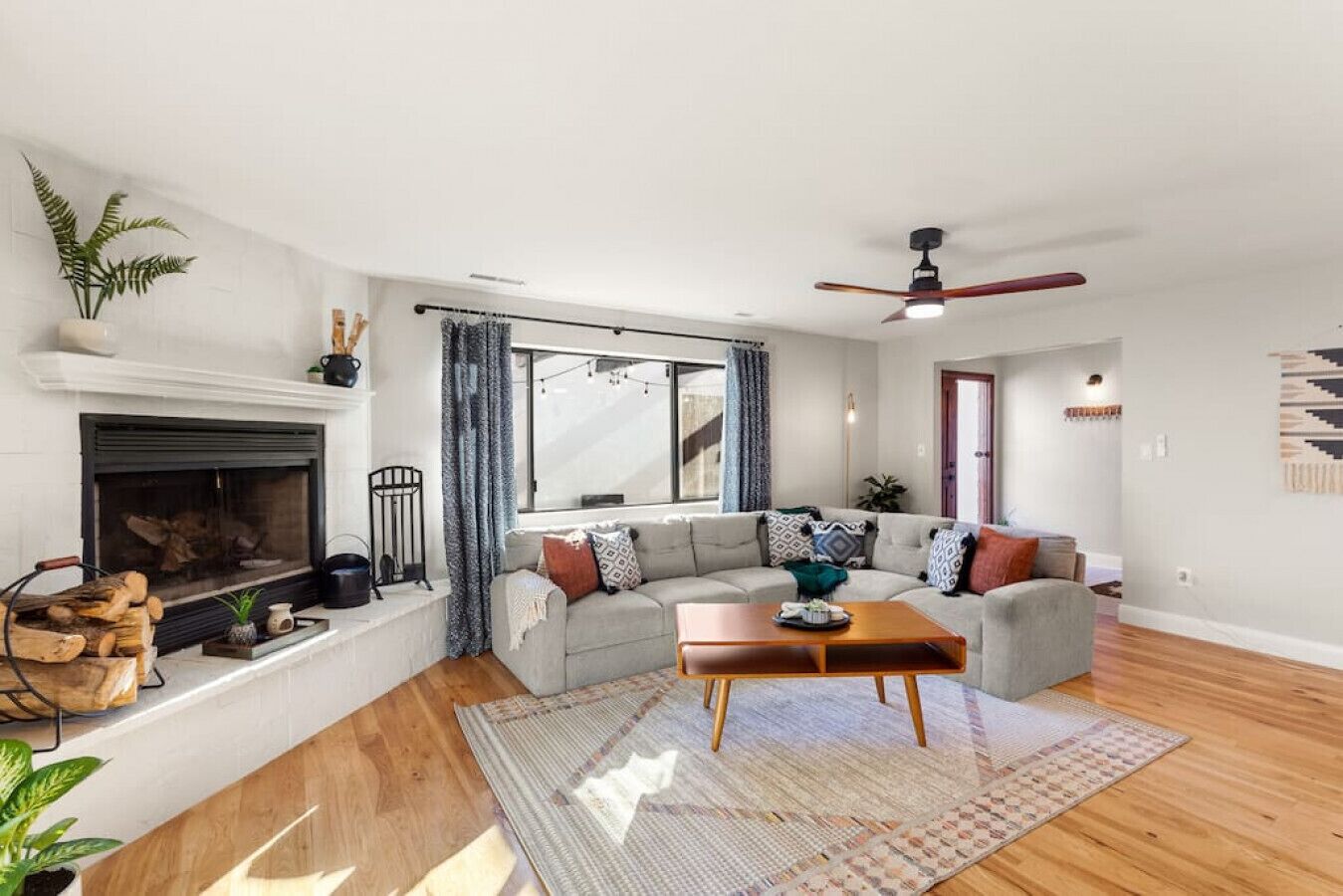 A modern living room with a fireplace, a sofa set, a coffee table, and a ceiling fan.