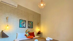 Un dormitorio con una cama grande, un lámpara colgante, dos lámparas de pared y dos cuadros enmarcados.
