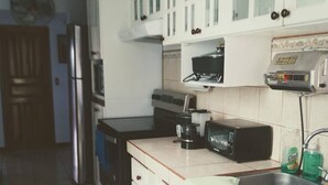 A kitchen with white cabinets, a microwave, a toaster, and a sink.