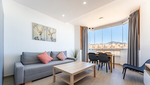A modern living room with a sofa, coffee table, and dining area.
