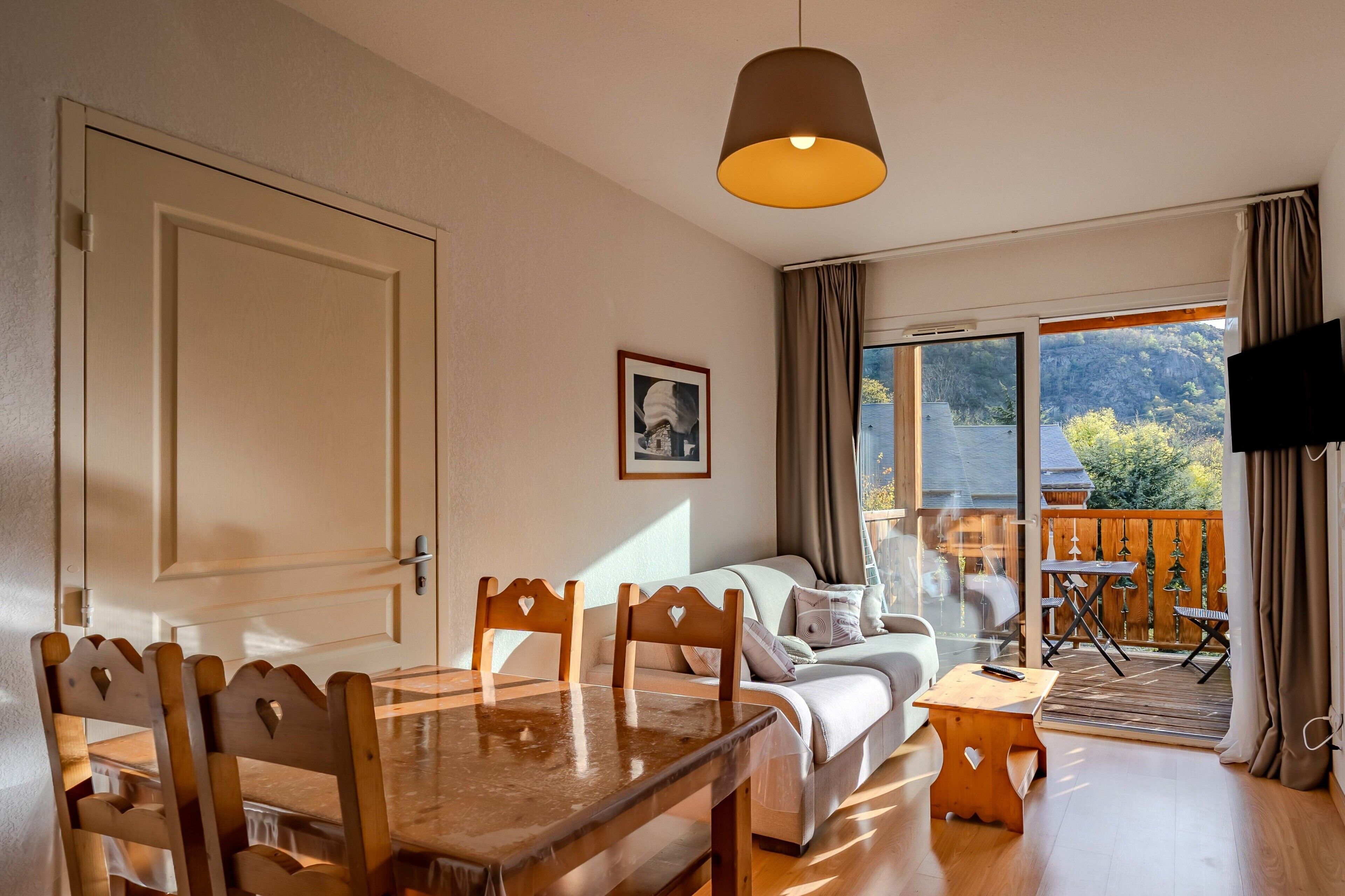 Une pièce comprenant un lit, une table à manger avec des chaises, un canapé, un téléviseur et donnant sur l’extérieur.