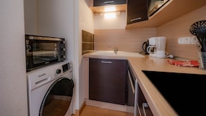 Une cuisine compacte équipée d’un lave-linge, d’un four à micro-ondes, d’une machine à café et d’un évier.
