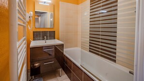 Une salle de bain avec un lavabo blanc, un miroir et une baignoire.