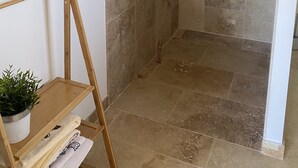 Zona de ducha con azulejos color beige, una escalera de madera y una planta en maceta.