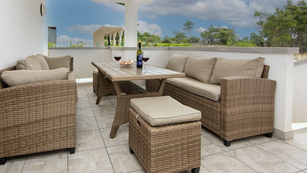 A patio area with wicker furniture, a table, and a bottle of wine.