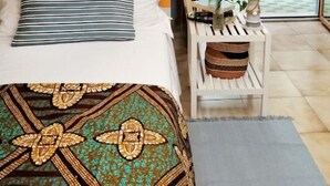 Une chambre à coucher avec un lit, une table de chevet ornée d’une plante, et une vue sur l’extérieur.