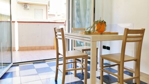 Un balcon avec un sol à carreaux, une table avec des chaises et une plante en pot.