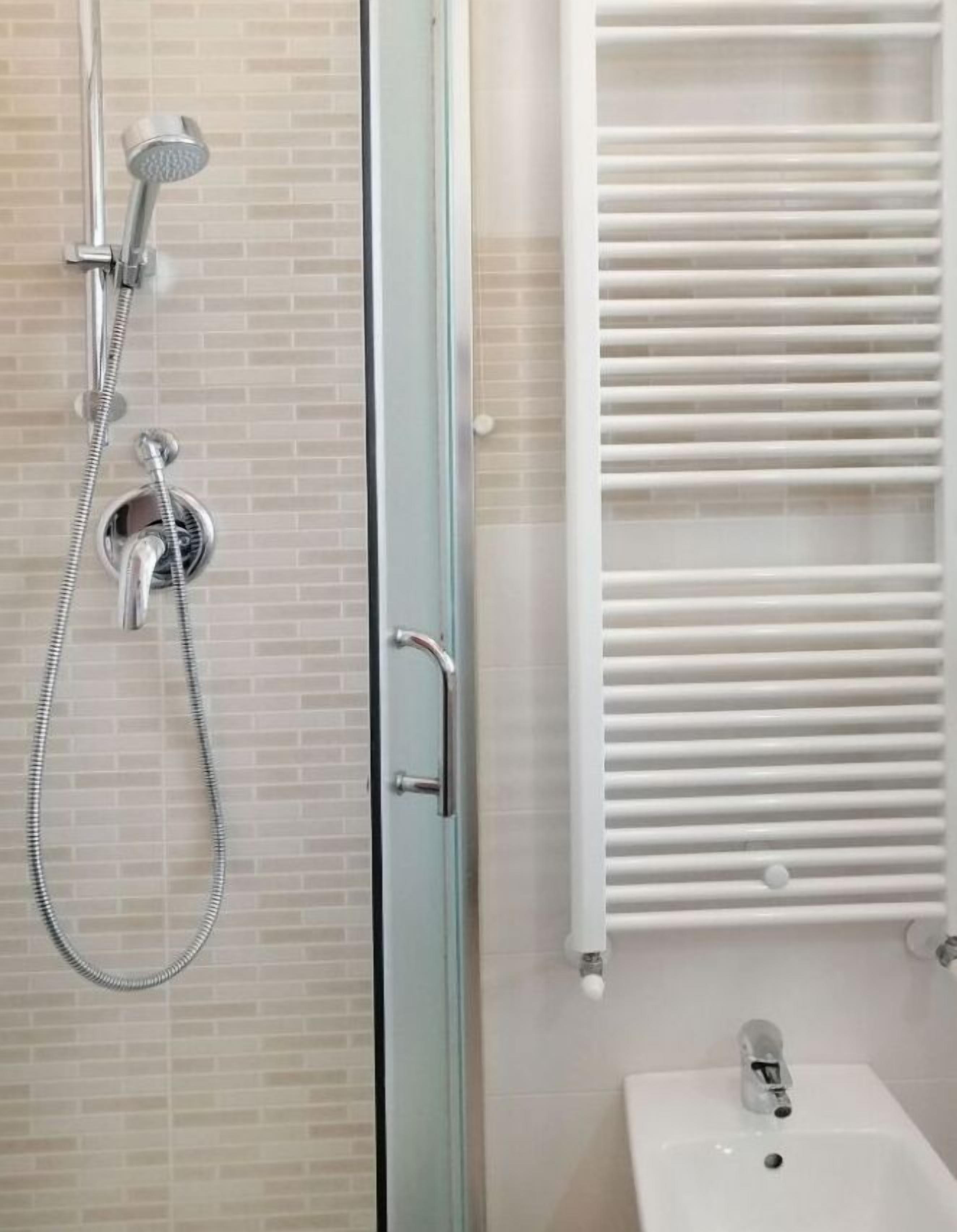 Une salle de bain avec une douche à parois de verre, un lavabo blanc et un porte-serviettes.