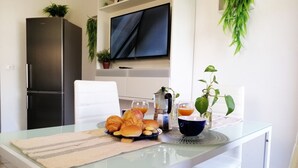 Una cocina moderna con una mesa de vidrio, alimentos para el desayuno y un televisor montado en la pared.