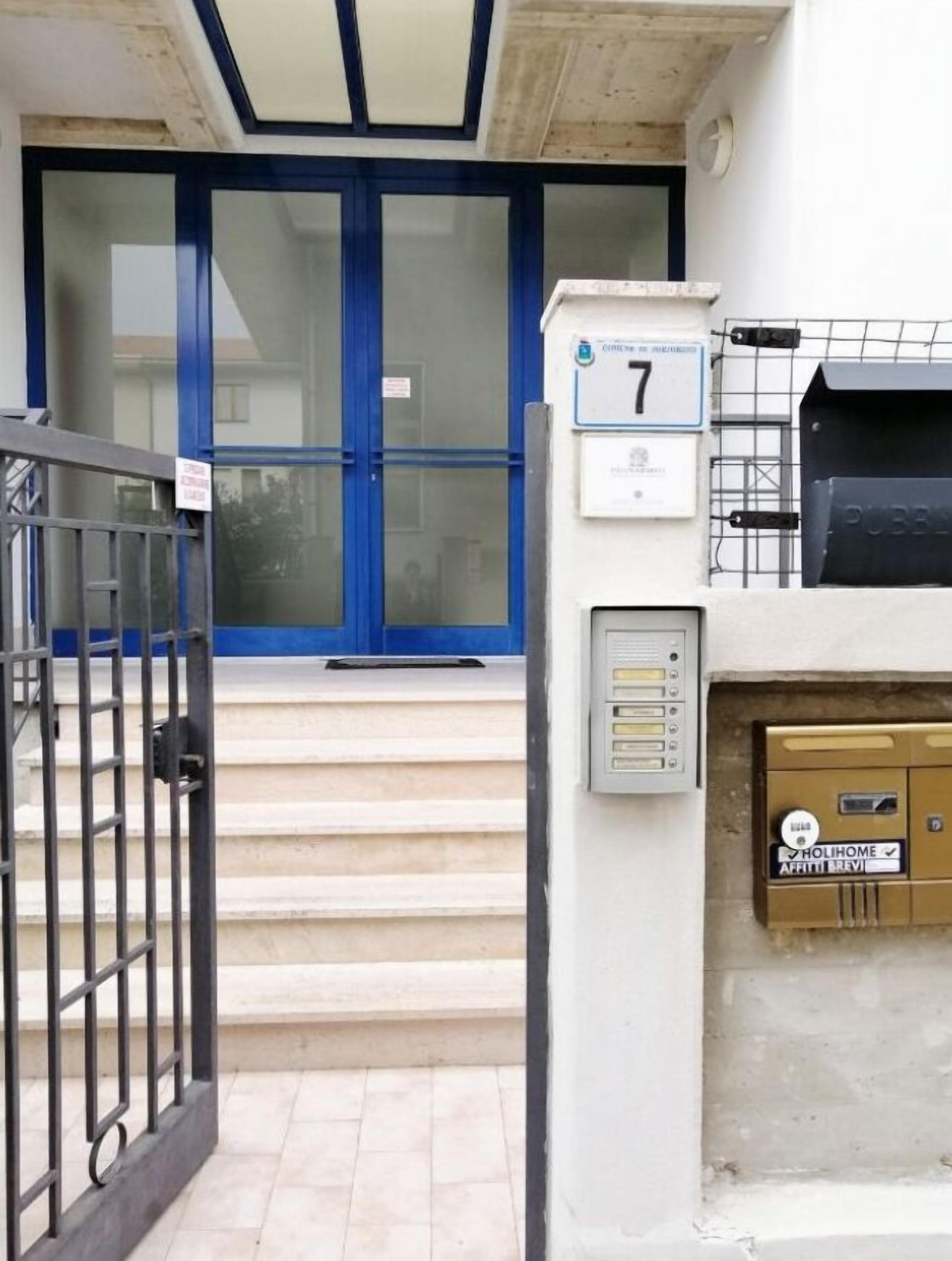 A building entrance with a blue door, a mailbox, and a small mailbox on the wall.