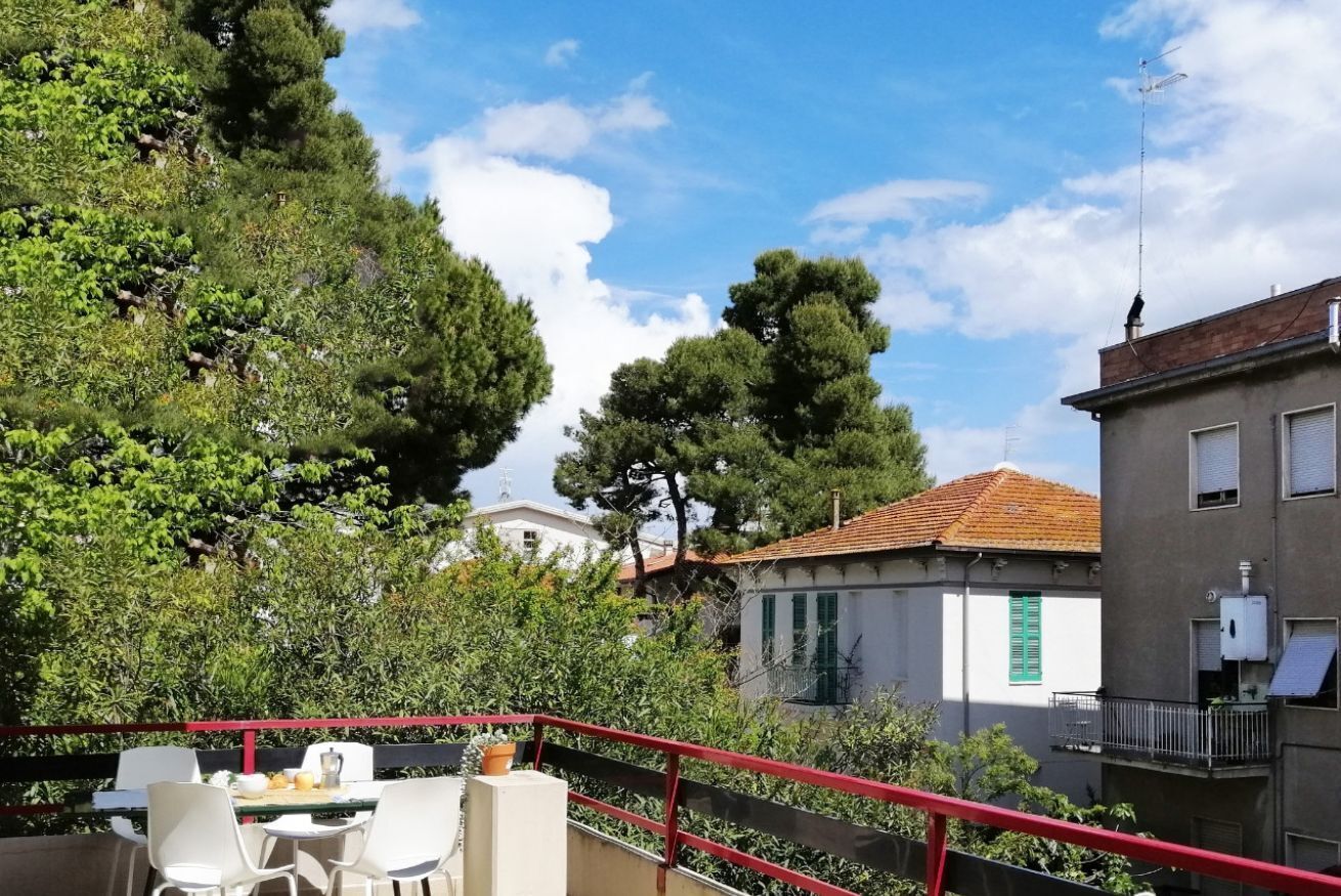 Une terrasse avec des places assises extérieures, entourée d’arbres et d’immeubles.