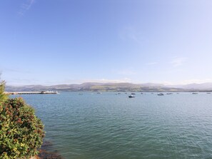A calm lake with boats, a bridge, and distant hills. - Cobblers Cottage (Beaumaris)
