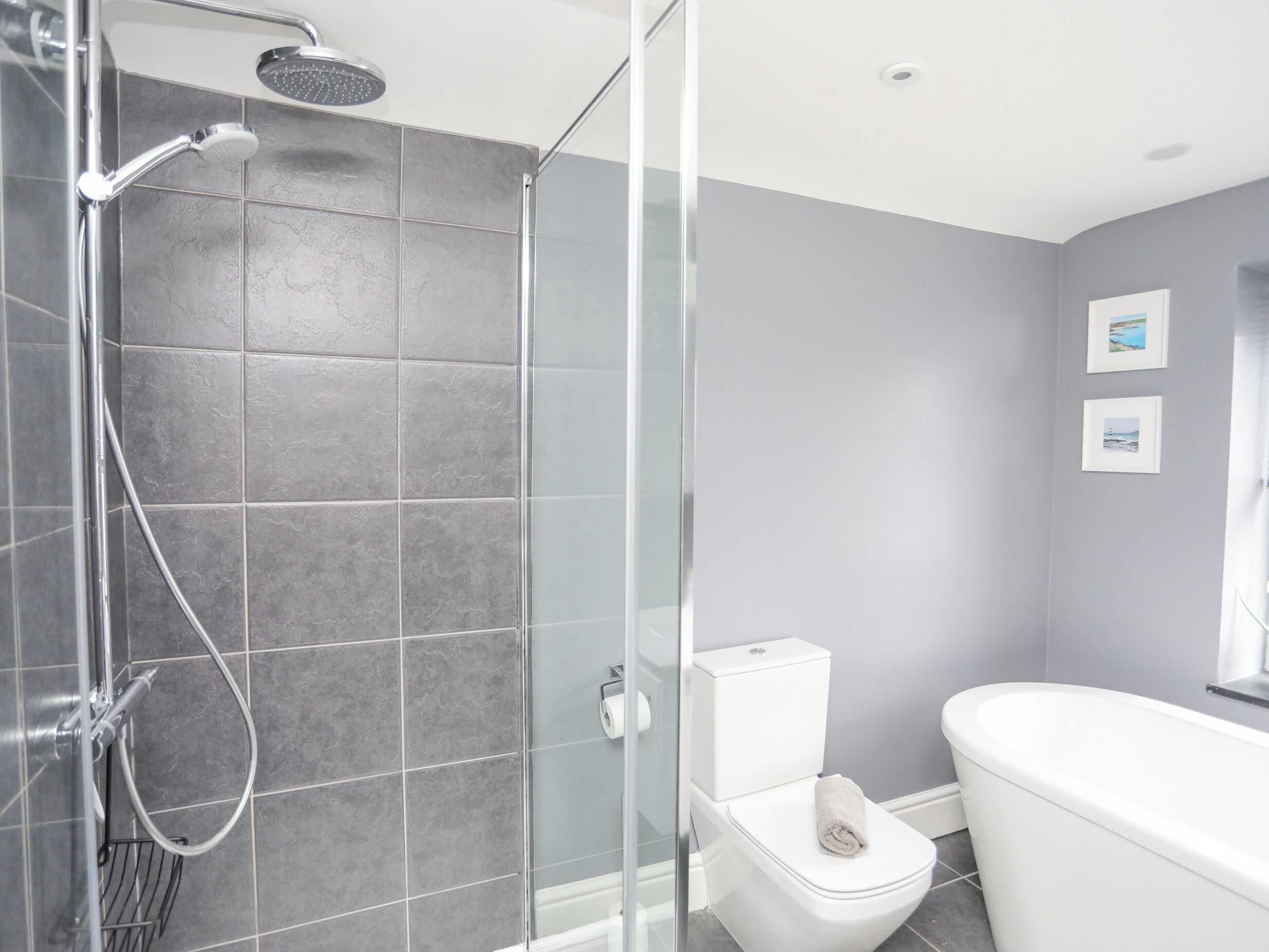 Une salle de bain moderne avec une douche à parois de verre, des toilettes blanches et une baignoire.