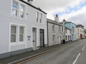 A row of white and grey townhouses with a clear road in front. - Cobblers Cottage (Beaumaris)