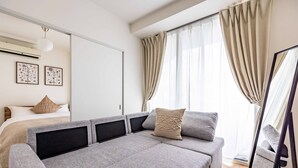 A modern bedroom with a sofa bed, a large mirror, and a bed with a headboard. - STAY 1ST (Osaka)