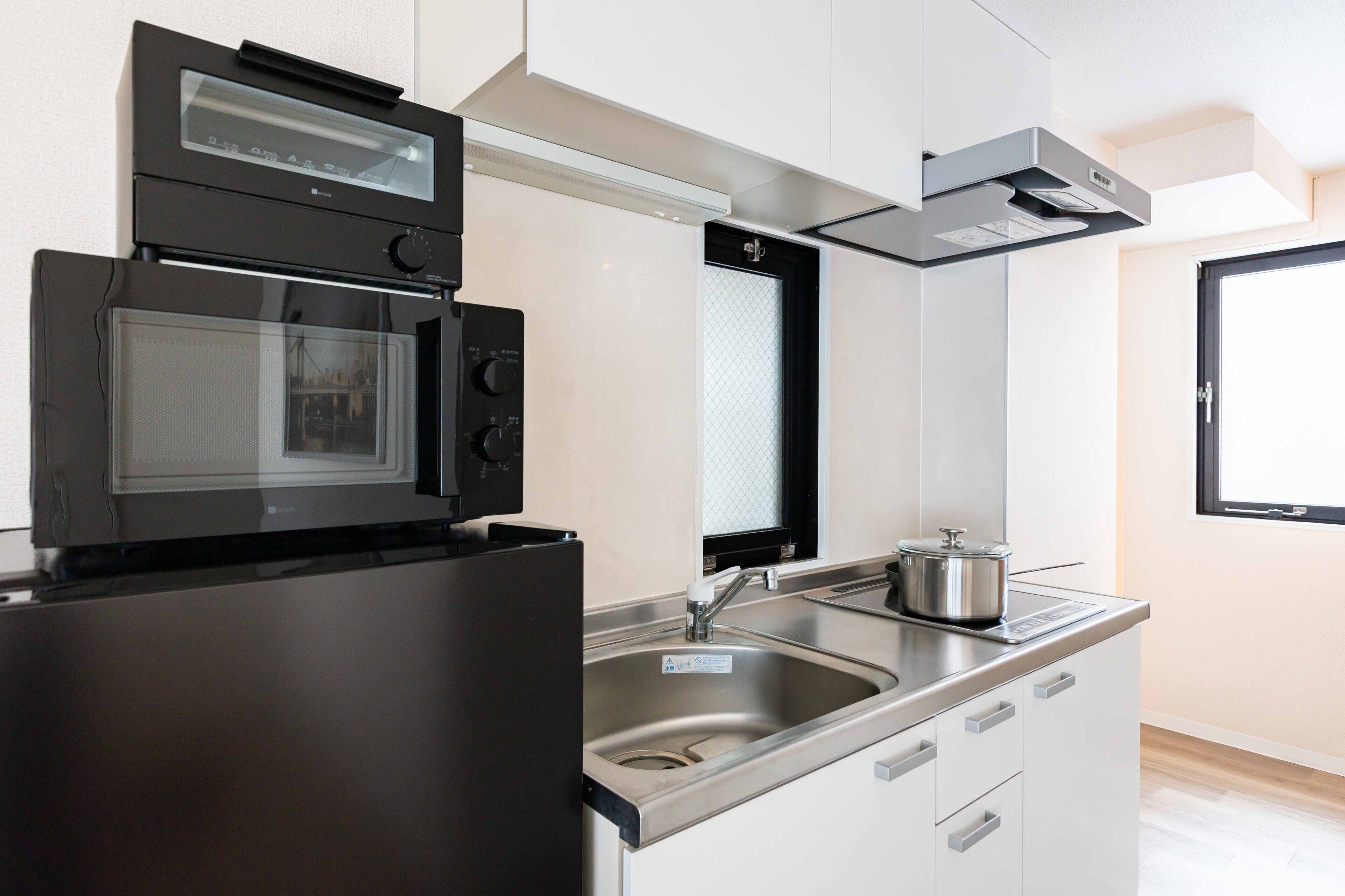 A modern kitchen with a built-in oven, microwave, and stainless steel sink.