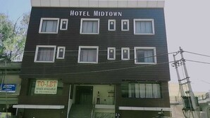 Et hotel kaldet "Hotel Midtown" med et skilt, der angiver ledige værelser, og en tydelig trappe til indgangen.