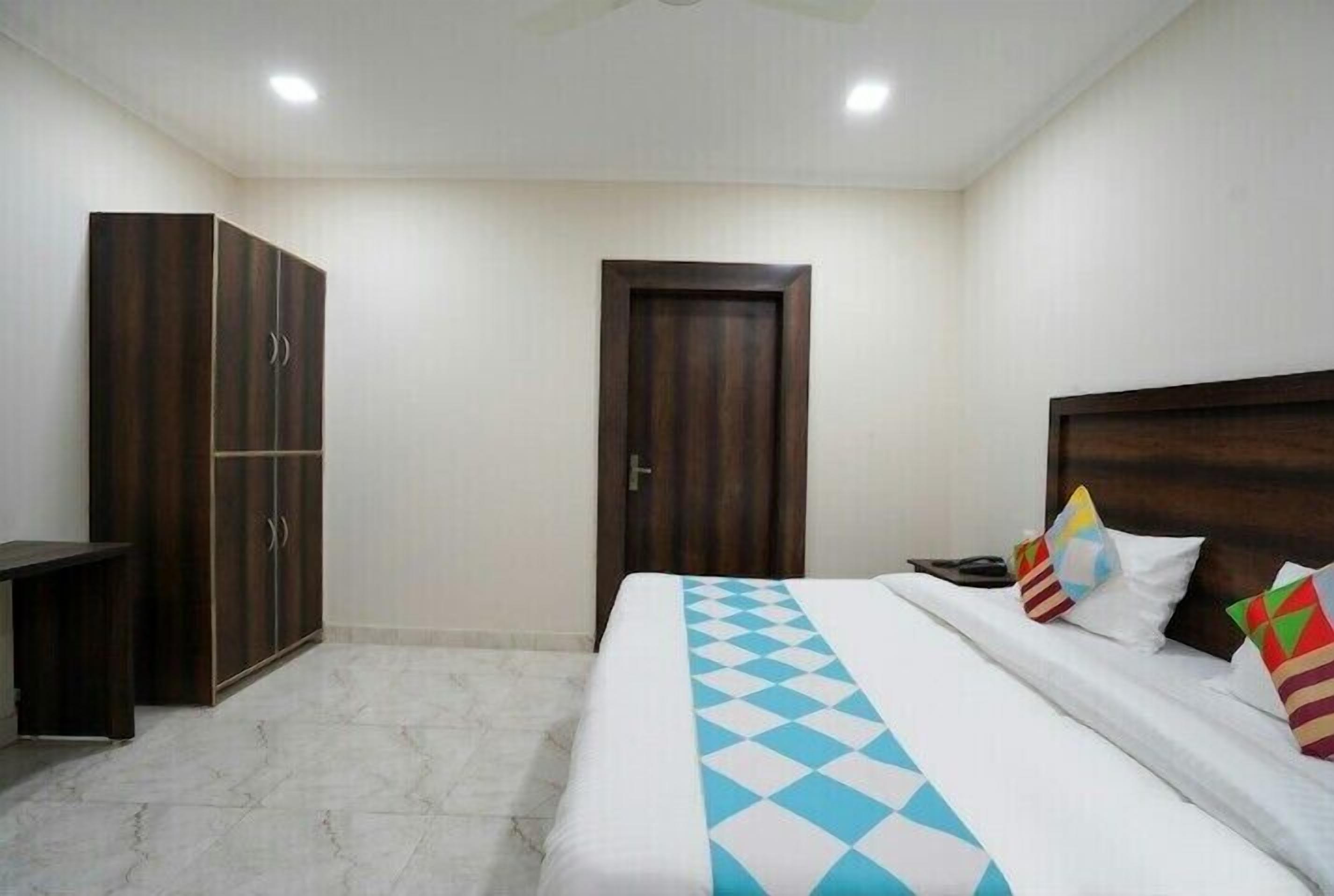 A bedroom with a bed, a wardrobe, a desk, and a door.