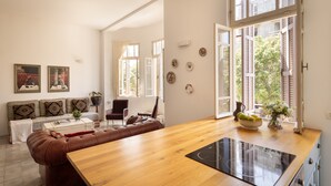 Eine moderne Küche mit Holzarbeitsplatte, Induktionskochfeld und Blick ins Freie durch offene Fenster.