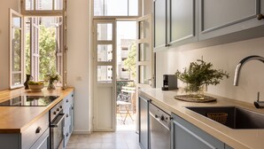 Eine moderne Küche mit großem Fenster, integrierten Geräten und Blick auf den Balkon.