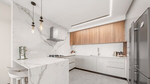 Eine moderne Küche mit weißen Marmorarbeitsplatten, Holzschränken und Edelstahlgeräten.