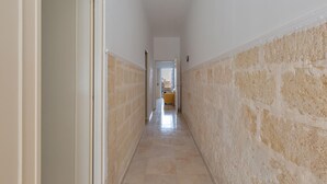 A narrow hallway with a tiled floor, white walls, and a stone accent wall. - 3550 Casa Cleopatra by Barbarhouse (Porto Cesareo)
