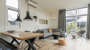 Ein modernes Wohnzimmer mit einem Holzesstisch, einer grauen Couch und einer schwarzen Lederecke.