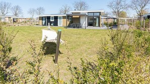Ein modernes Gebäude mit flachem Dach, großen Fenstern und einer überdachten Außen-Sitzgelegenheit.
