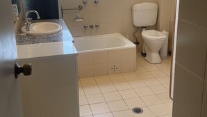 Une salle de bain avec un lavabo, une baignoire, des toilettes et une fenêtre.