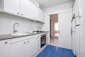 Eine moderne Küche mit weißen Schränken, einer Granit-Arbeitsplatte, einem Edelstahl-Spülbecken und einem eingebauten Backofen.