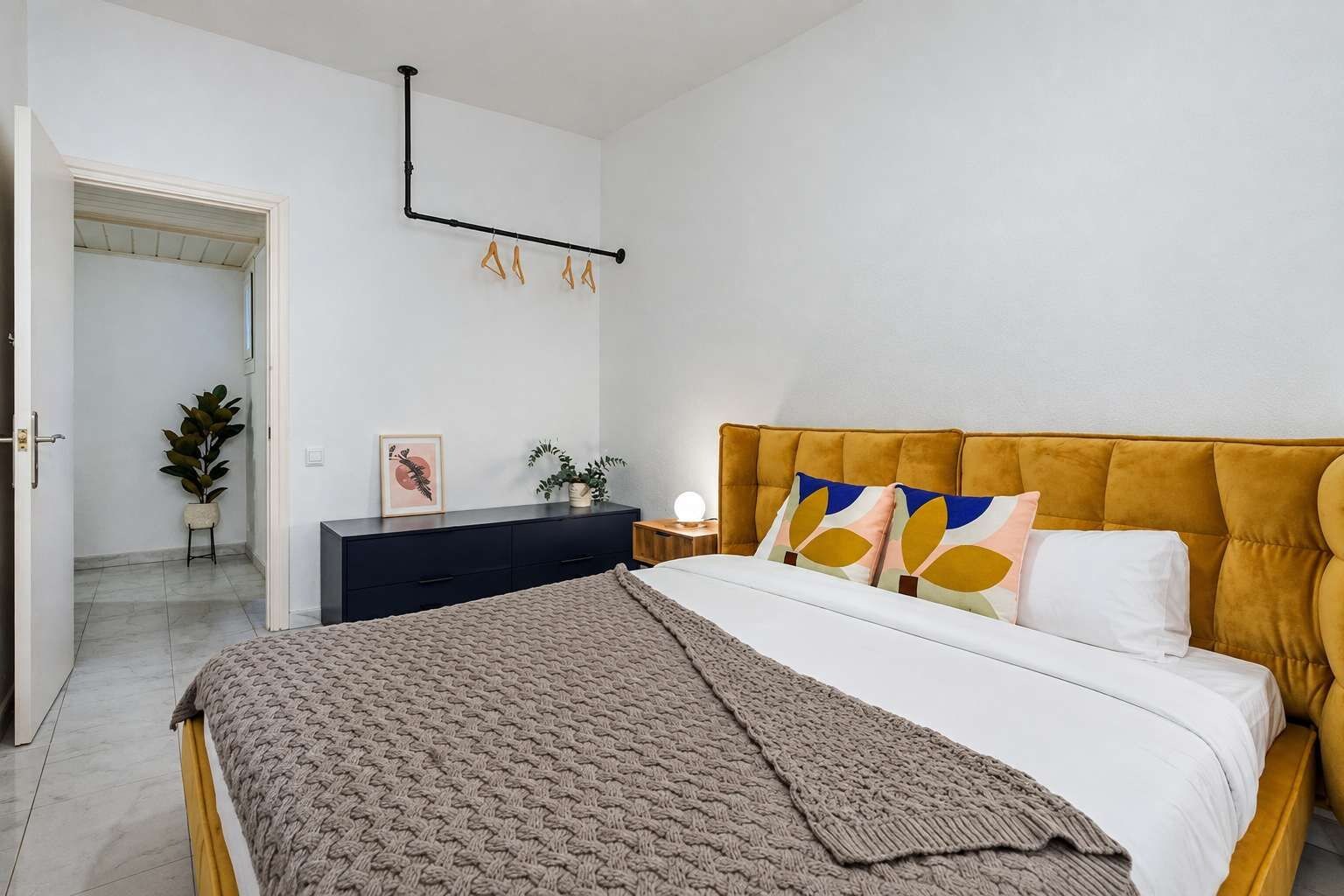 A bedroom with a bed, bedside table, and a wall-mounted light fixture.