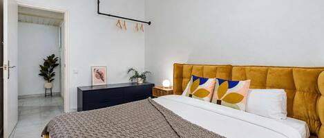 Un dormitorio con cama, mesita de noche y lámpara de pared.