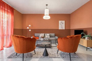 Ein modernes Wohnzimmer mit einer Couch, zwei Sesseln, einem Couchtisch und einem Fernseher.