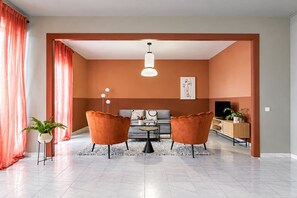 Un salon moderne comprenant un canapé, deux fauteuils, une table basse et un téléviseur.