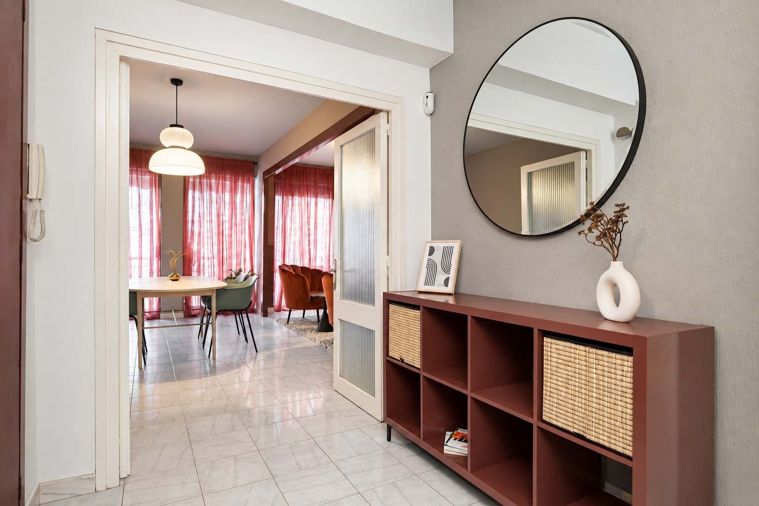 A modern living room with a dining area, a round mirror, and a console table with baskets.