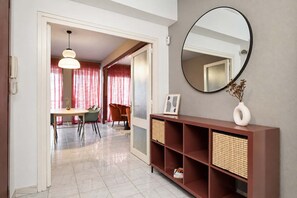 Un salon moderne comprenant un coin repas, un miroir rond et une console agrémentée de paniers.